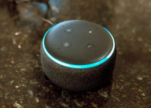 In this photo illustration, Echo Dot smart speaker with working Alexa with blue light ring seen displayed.