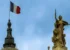 A French flag flutters atop a building (Pourya Gohari/Unsplash)