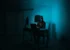 A hooded figure sits in front of a laptop screen in a darkened room. (Kartik Programmer/Unsplash)