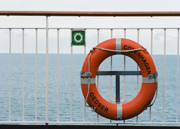 A lifesaving ring hangs on a iron fence overlooking the sea. (Credit: